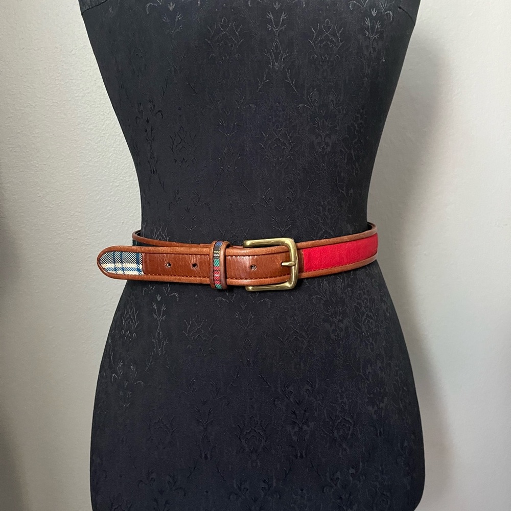 Brown leather belt with brass buckle and assorted plaid decor.